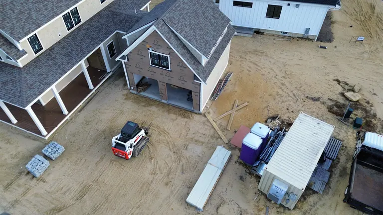 Unfinished ground and driveway beside the gray house