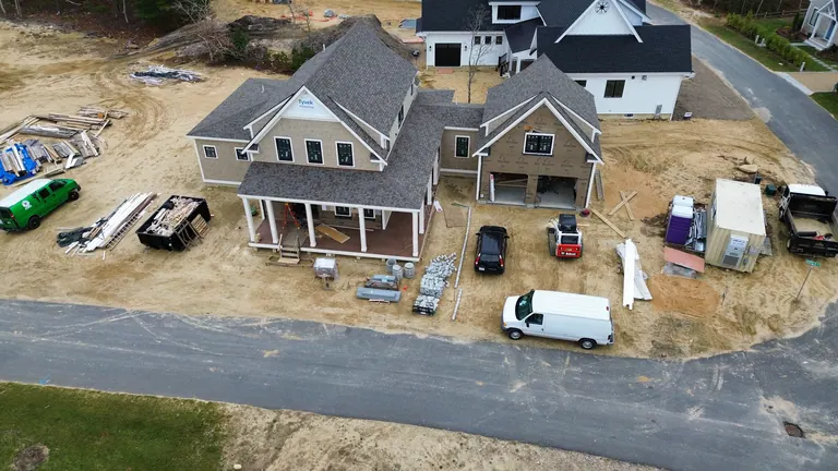 Gray-shingle home with exposed ground and construction materials