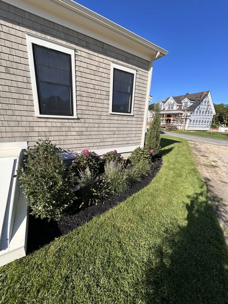 Mulched foundation planting bed beside the gray-shingle house