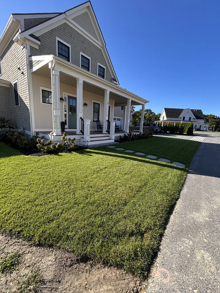Front garden and installed lawn beside the gray-shingle porch