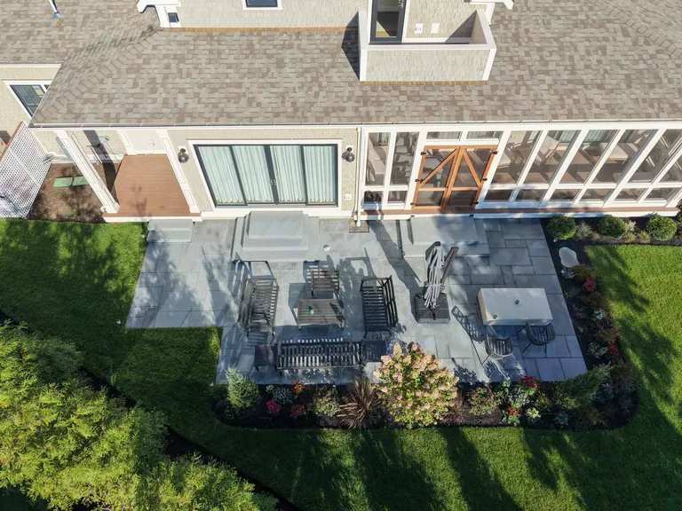 Overhead view of the rectangular stone terrace beside the gray-shingle home
