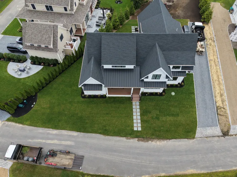 The same white home with finished lawn and a stone entrance path