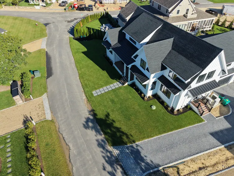 Finished lawn and stone paths around a white home with a dark roof
