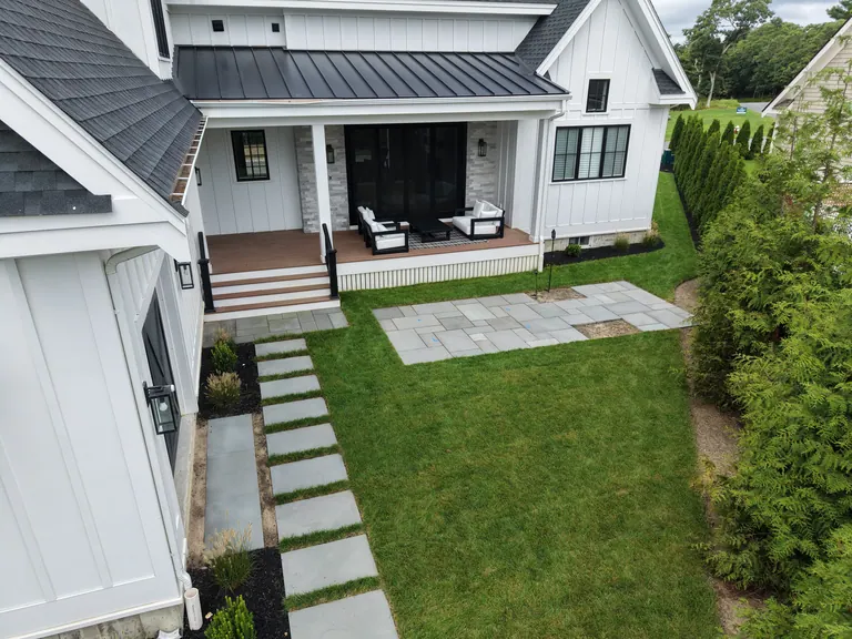 Finished rectangular stone patio and path behind the white house