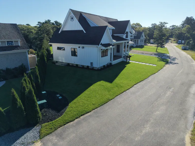 Finished side lawn beside the white house with a dark roof
