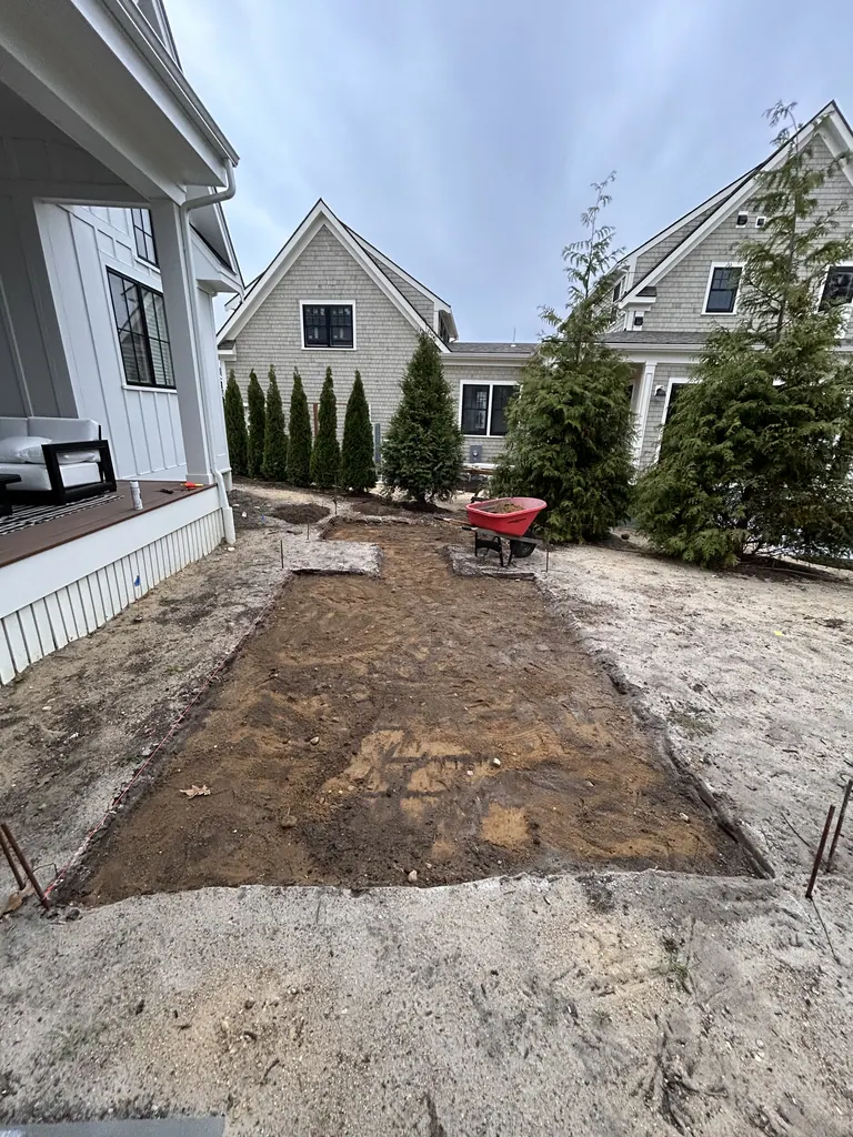 Excavated rectangular patio base beside the white house
