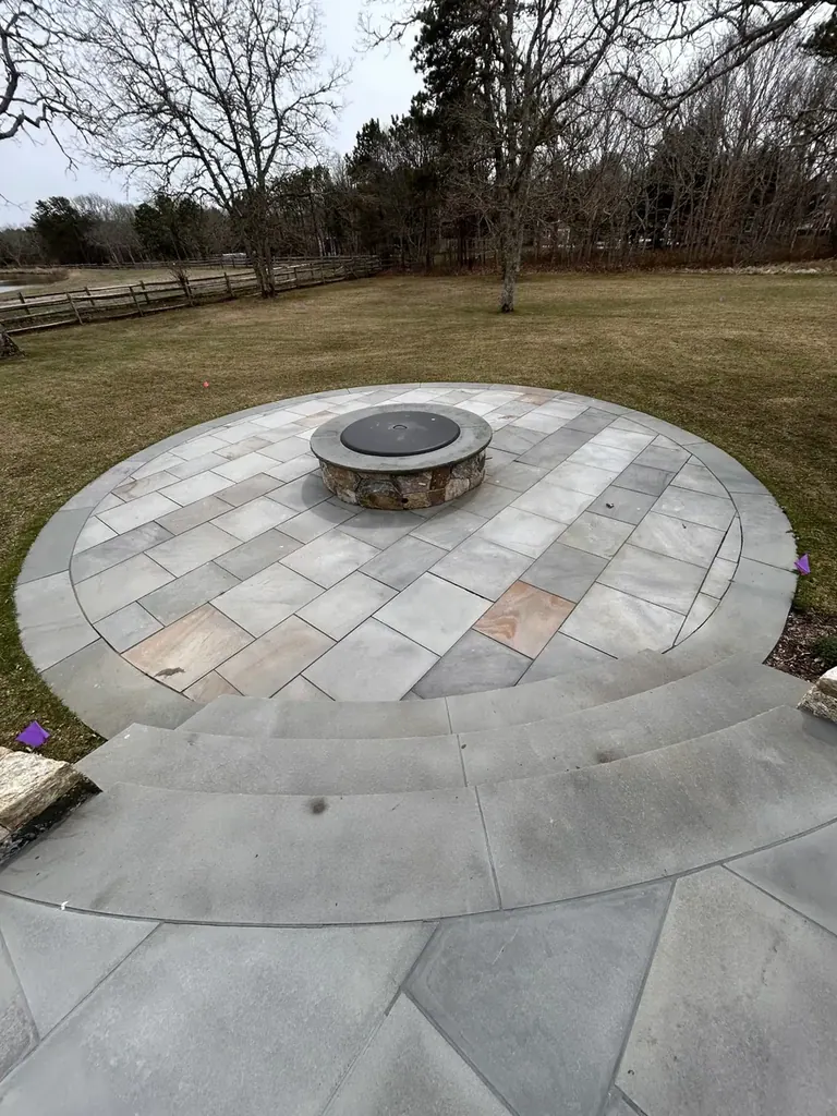 Round bluestone patio with a built-in fire pit on a Martha's Vineyard property