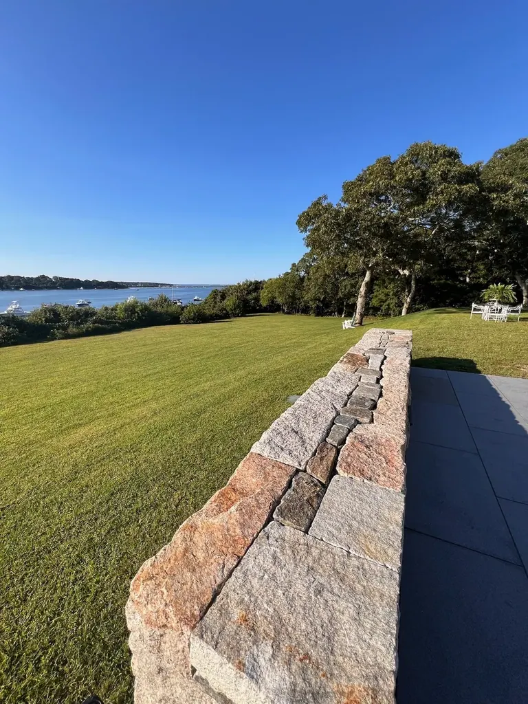 Curved natural-stone retaining wall along a waterfront Martha's Vineyard lawn