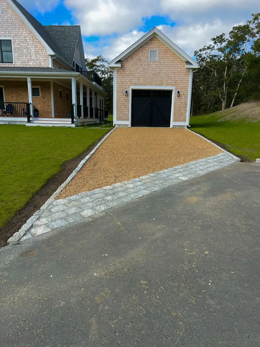 Finished cobblestone apron and pea gravel driveway leading to a garage