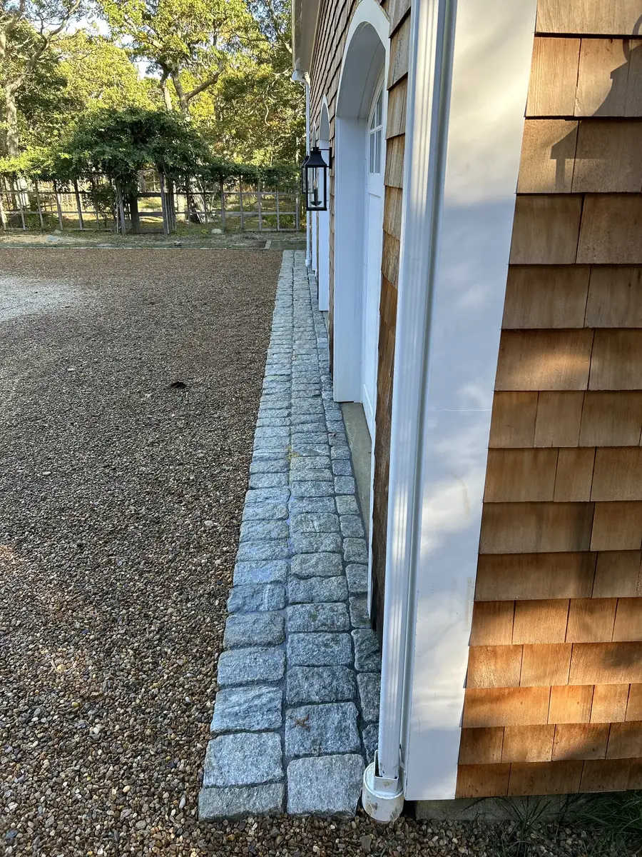 Granite cobblestone drip edge along a cedar-shingled garage