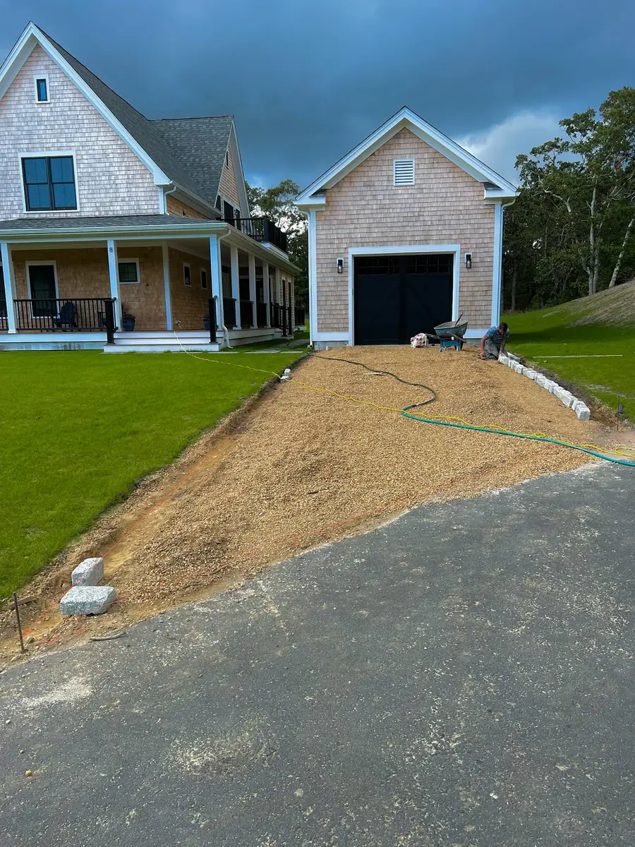Driveway base prepared between new lawn edges leading to a detached garage