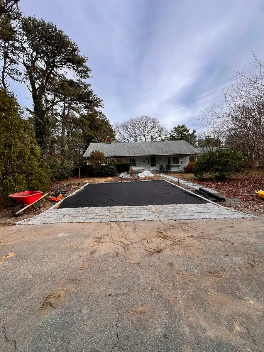 New asphalt driveway with a cobblestone apron at the road in front of a ranch house