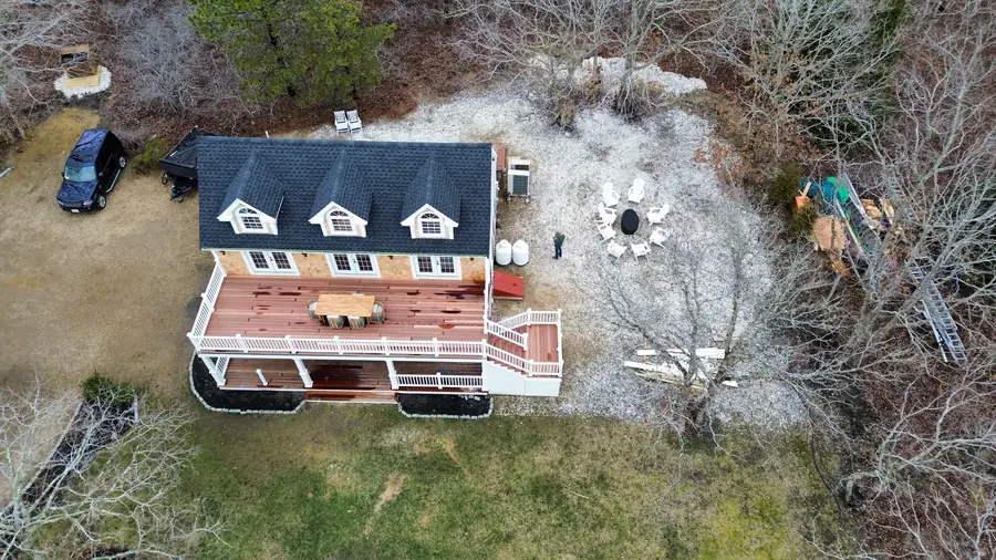 Aerial view of a house, deck and fire pit area in a wooded yard