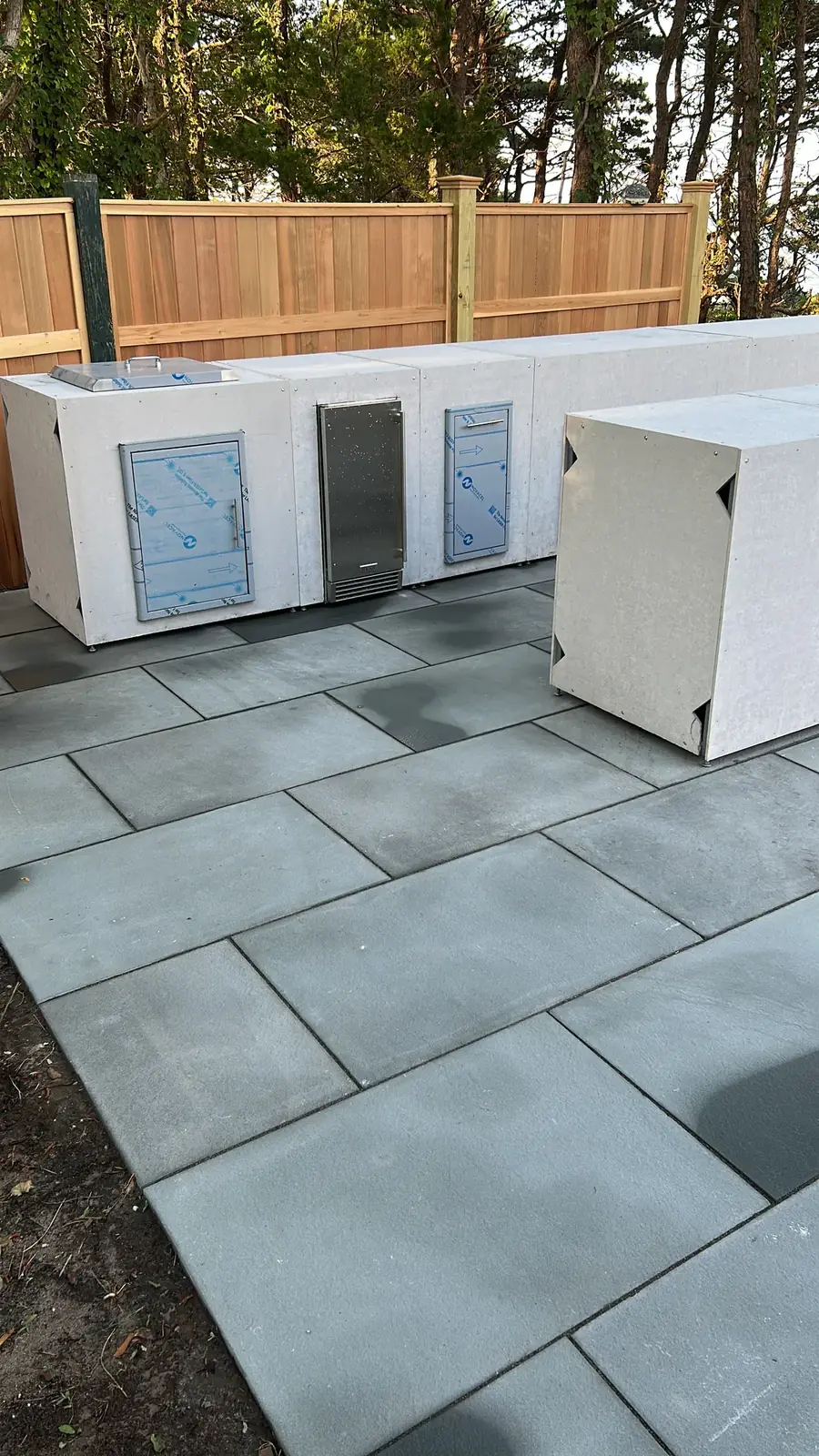 Outdoor kitchen island frames with appliance cutouts on a new bluestone patio