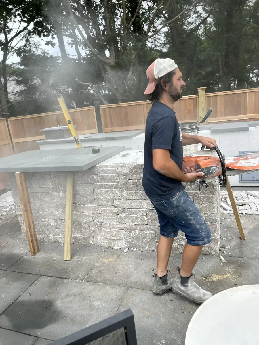 Crew member applying stone veneer to an outdoor kitchen island