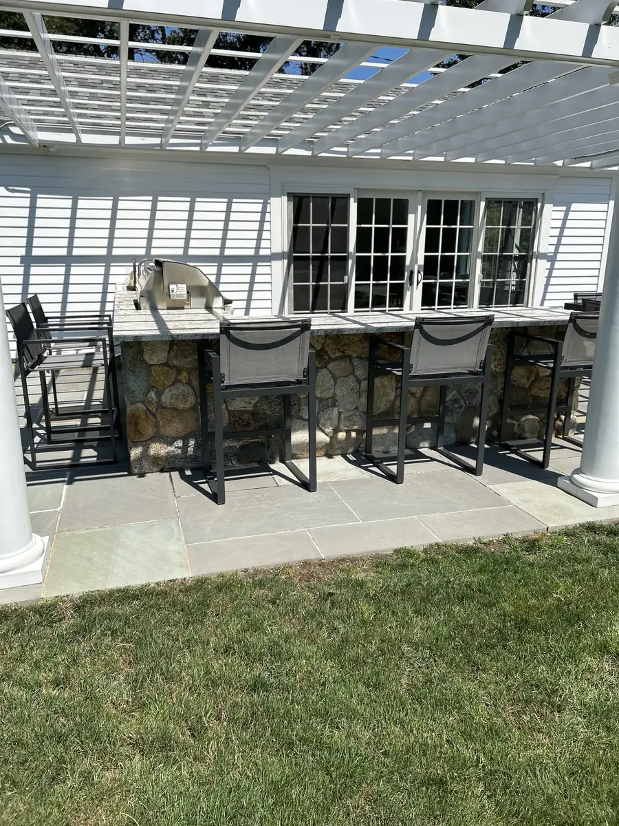Fieldstone bar with stools on a bluestone patio under a pergola