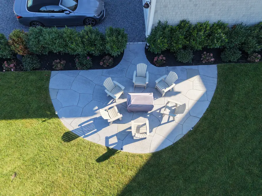 Aerial view of a circular bluestone fire pit patio set into a green lawn