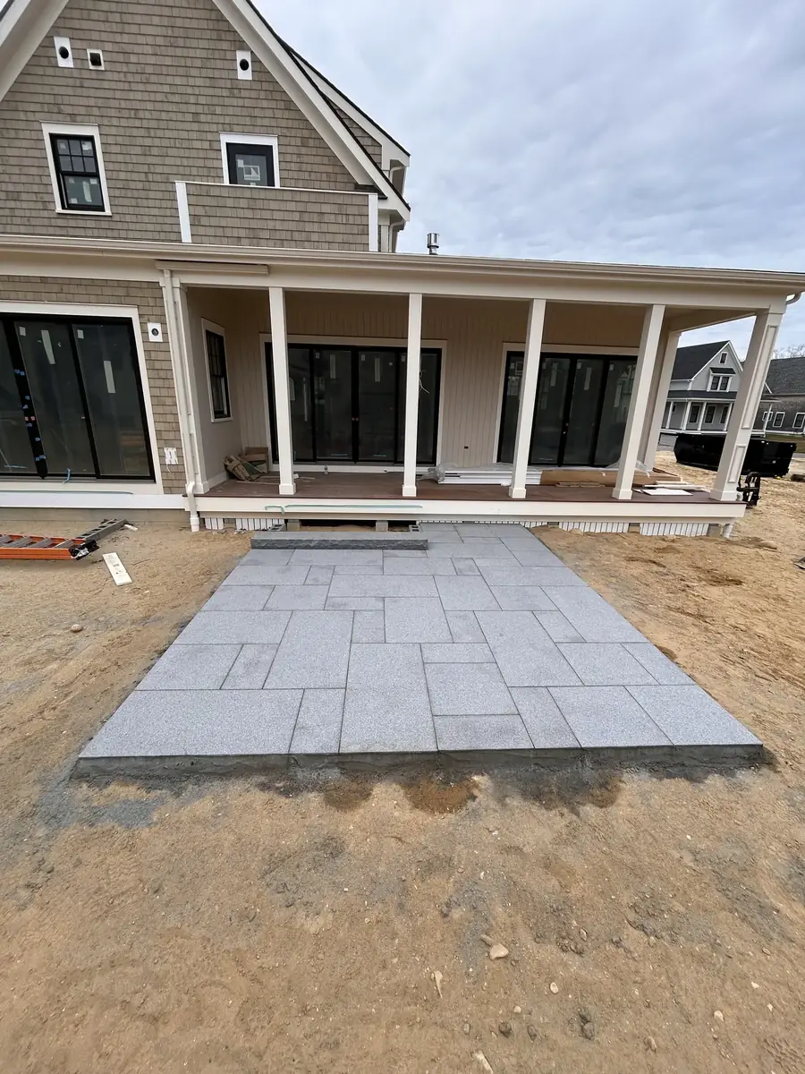 Pattern bluestone patio set on a prepared base in front of a new porch on a sandy lot