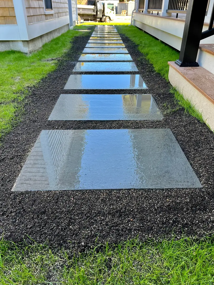 Large rectangular bluestone steppers set in dark gravel along a new house