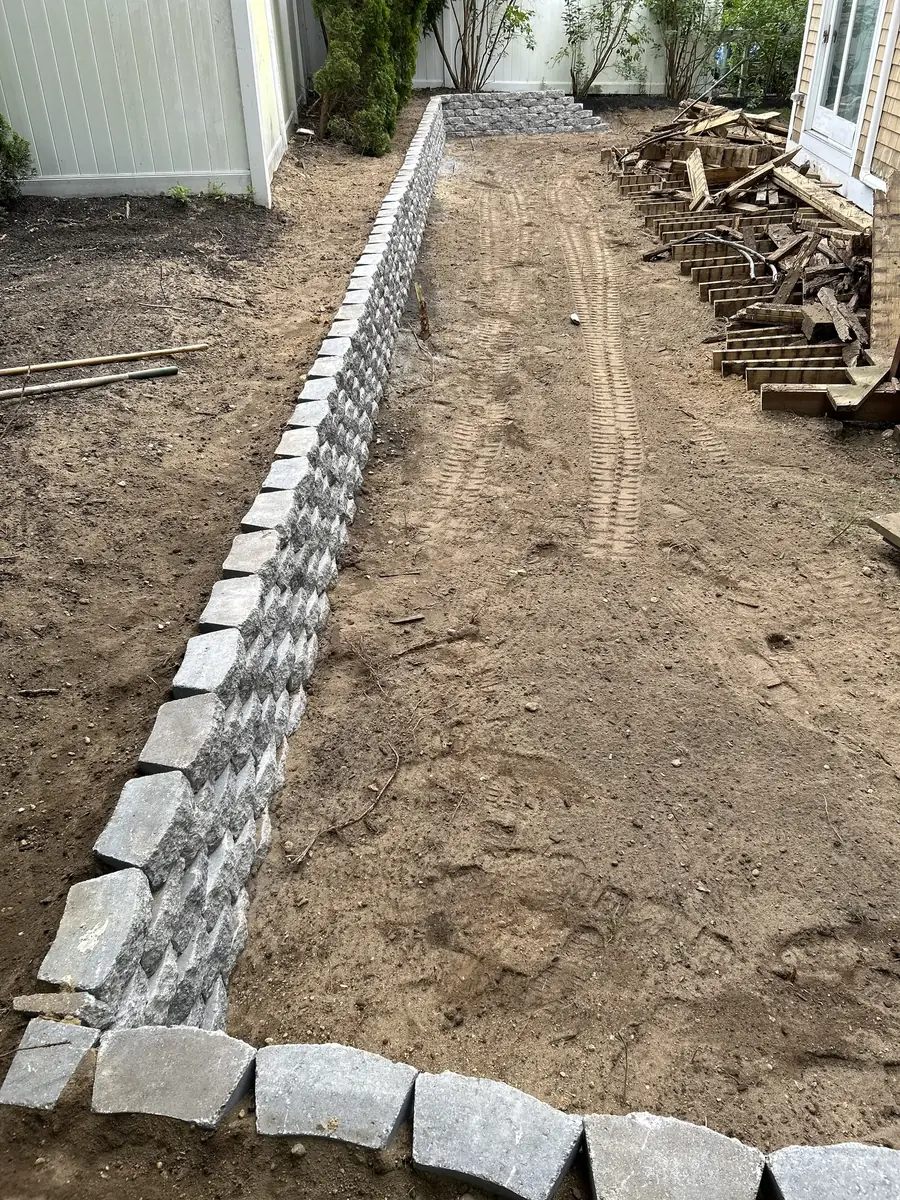 Long run of new segmental block retaining wall along a backyard fence