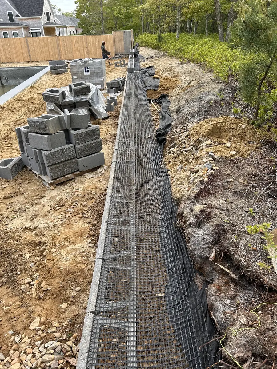Segmental block retaining wall with geogrid reinforcement laid into the backfill