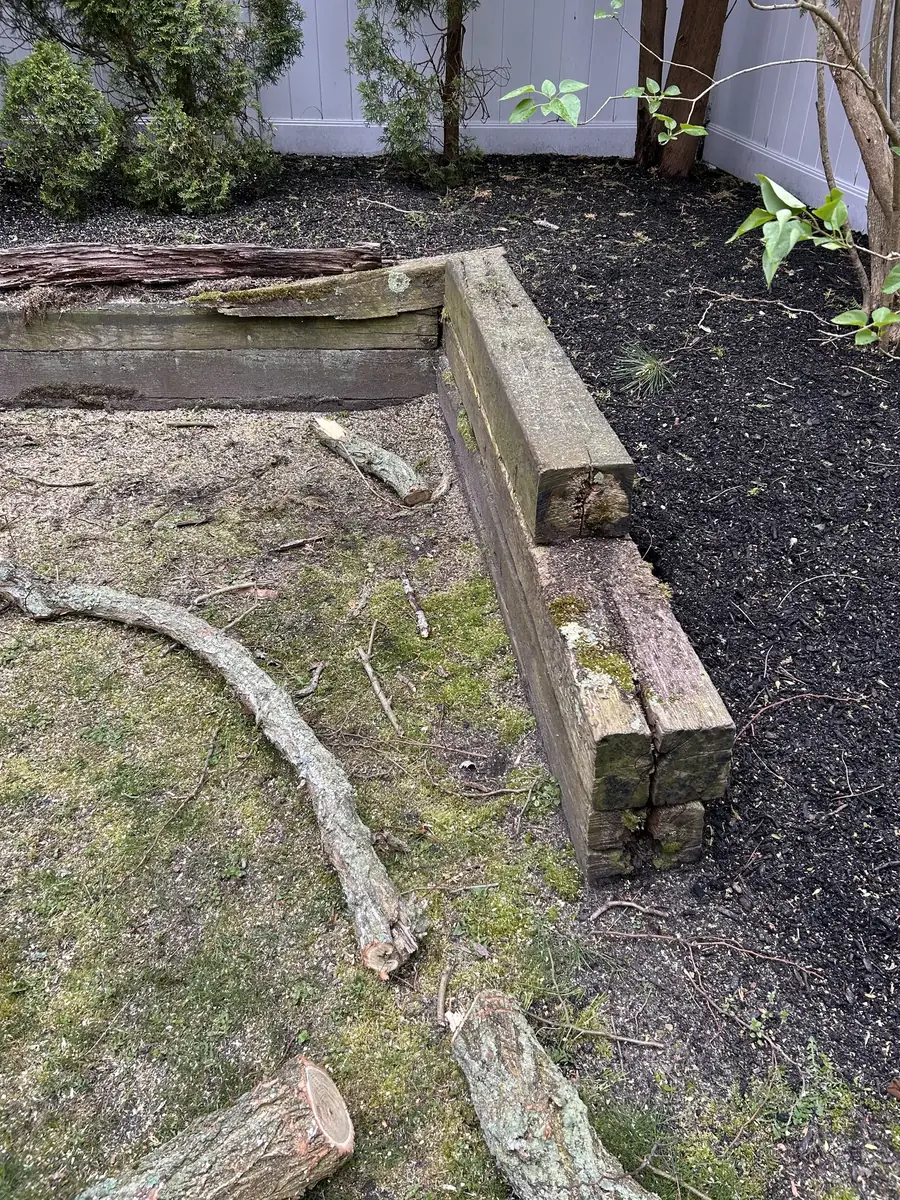 Old rotting landscape timber retaining wall before replacement