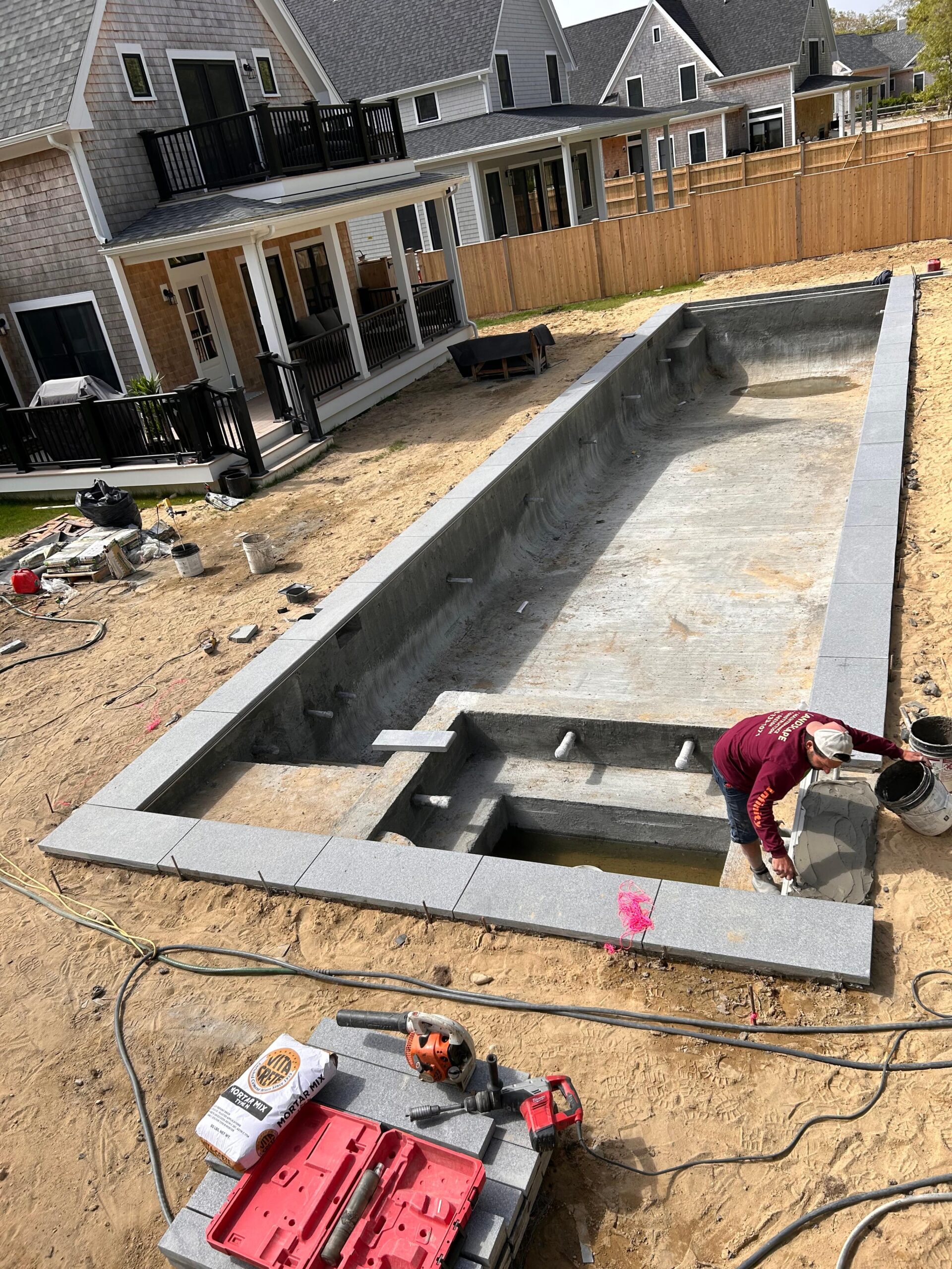 Pool coping installation in progress with stone placement on Martha’s Vineyard
