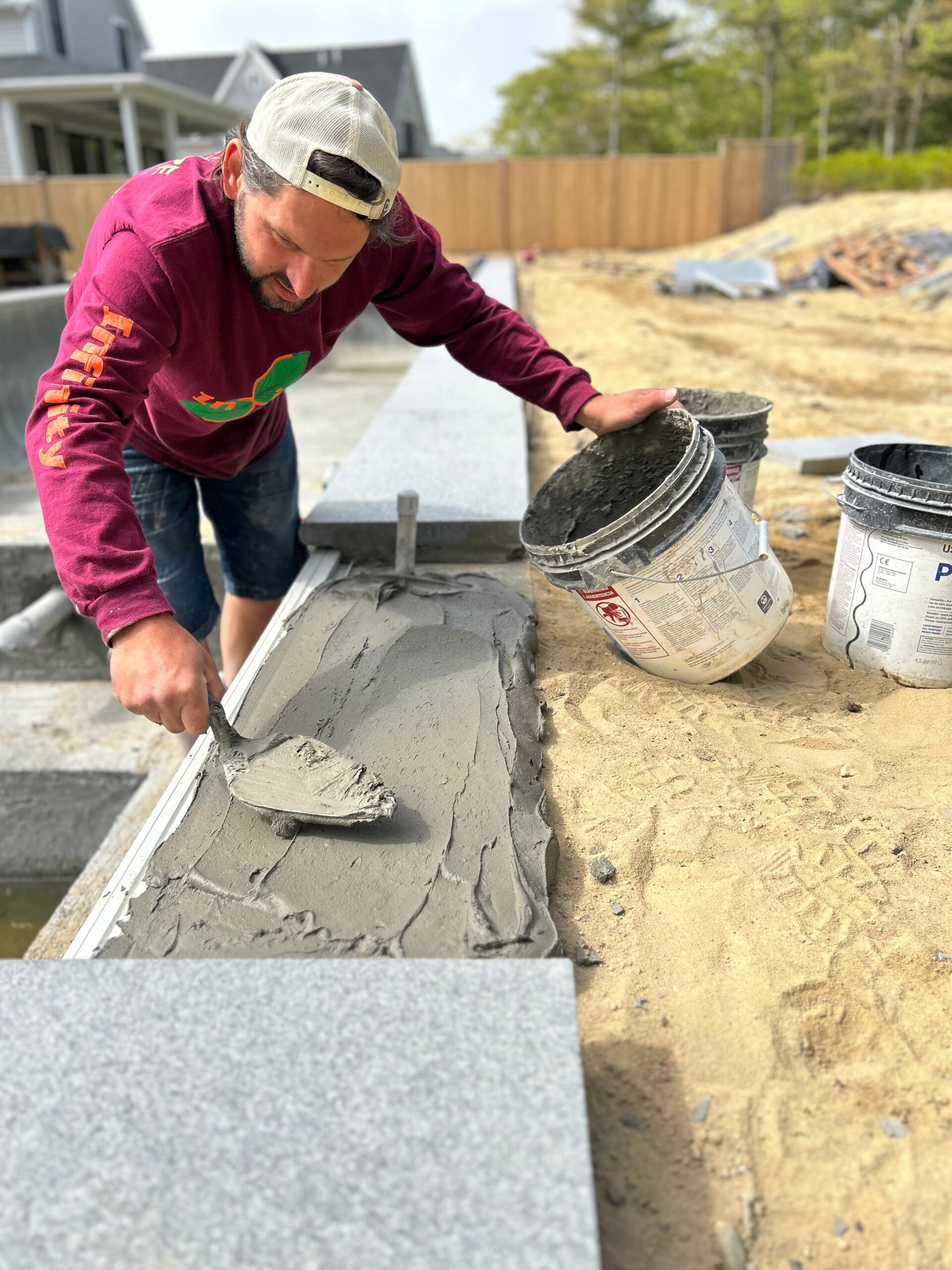 Pool coping installation with natural stone surrounding a swimming pool on Martha’s Vineyard