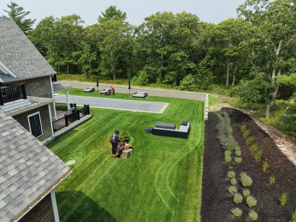 Aerial view of a backyard lawn being mowed beside planting beds