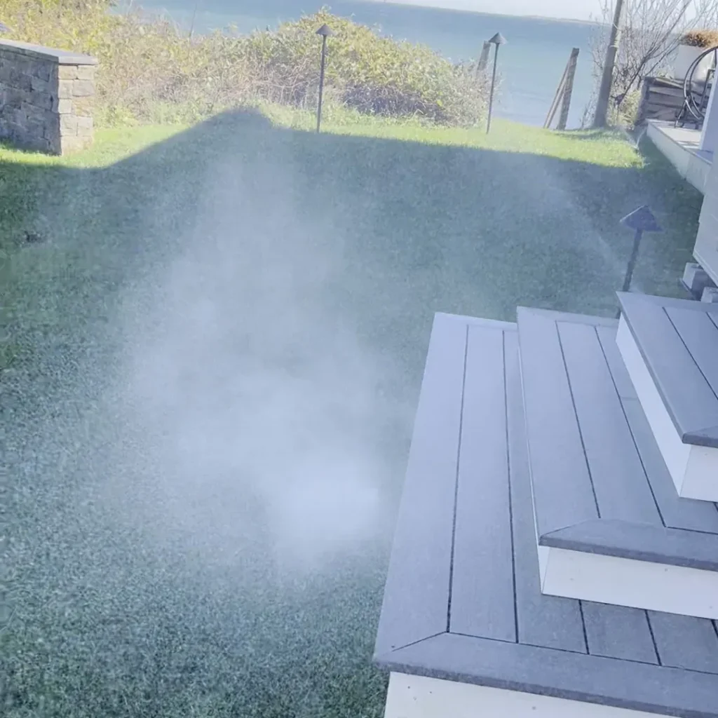 Air blowout mist over an oceanfront lawn beside composite deck steps