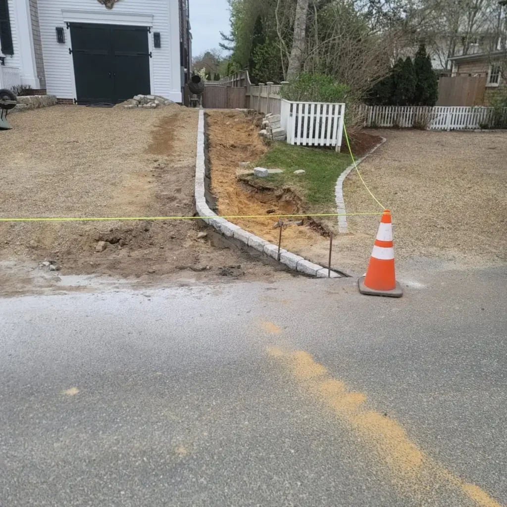 Cobblestone curb row being set at the street beside a traffic cone