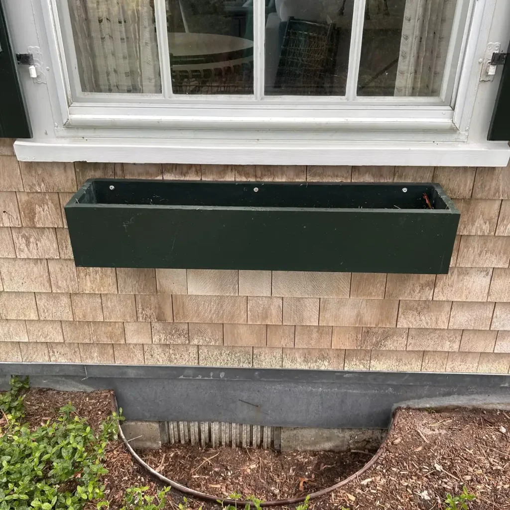 Empty window box mounted under a window before planting