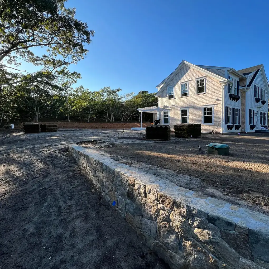 Fieldstone retaining wall holding a raised yard at a new house