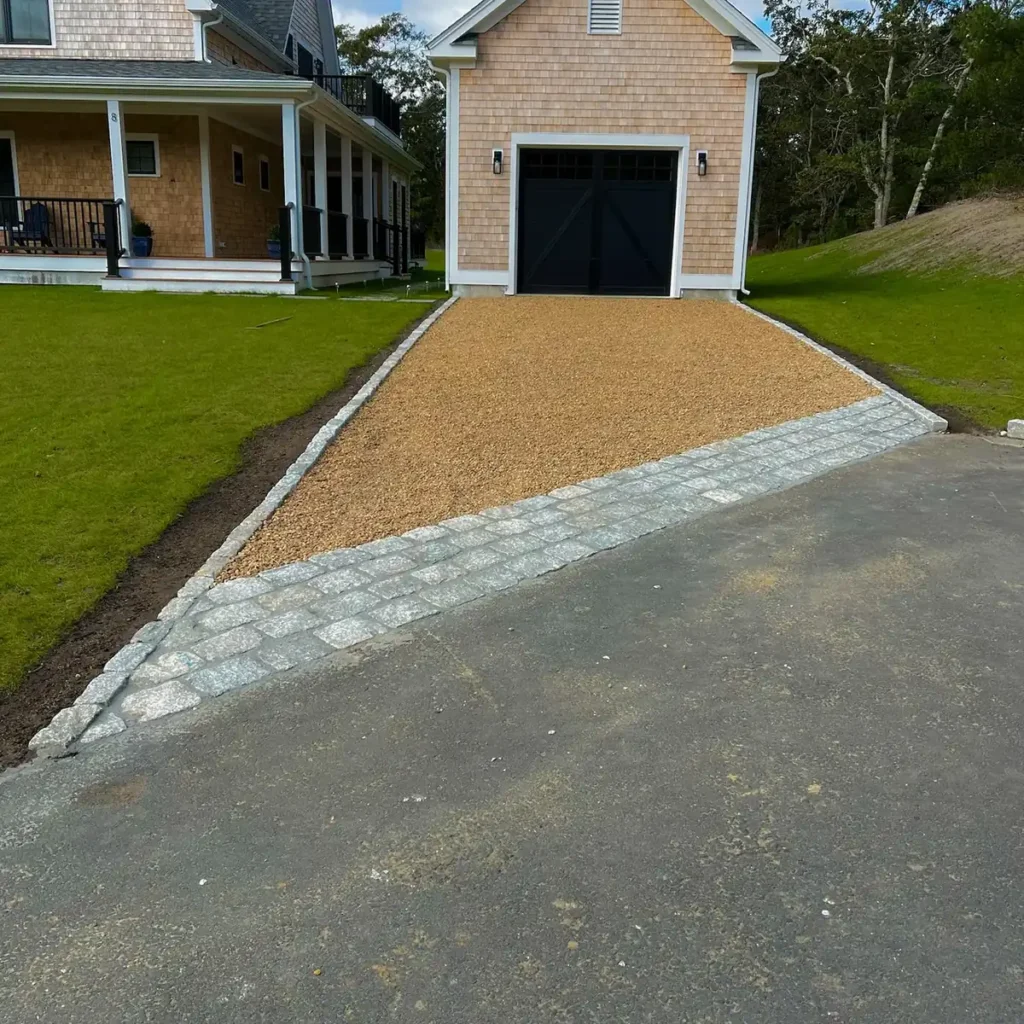 Finished cobblestone apron leading from the road to a shingled garage