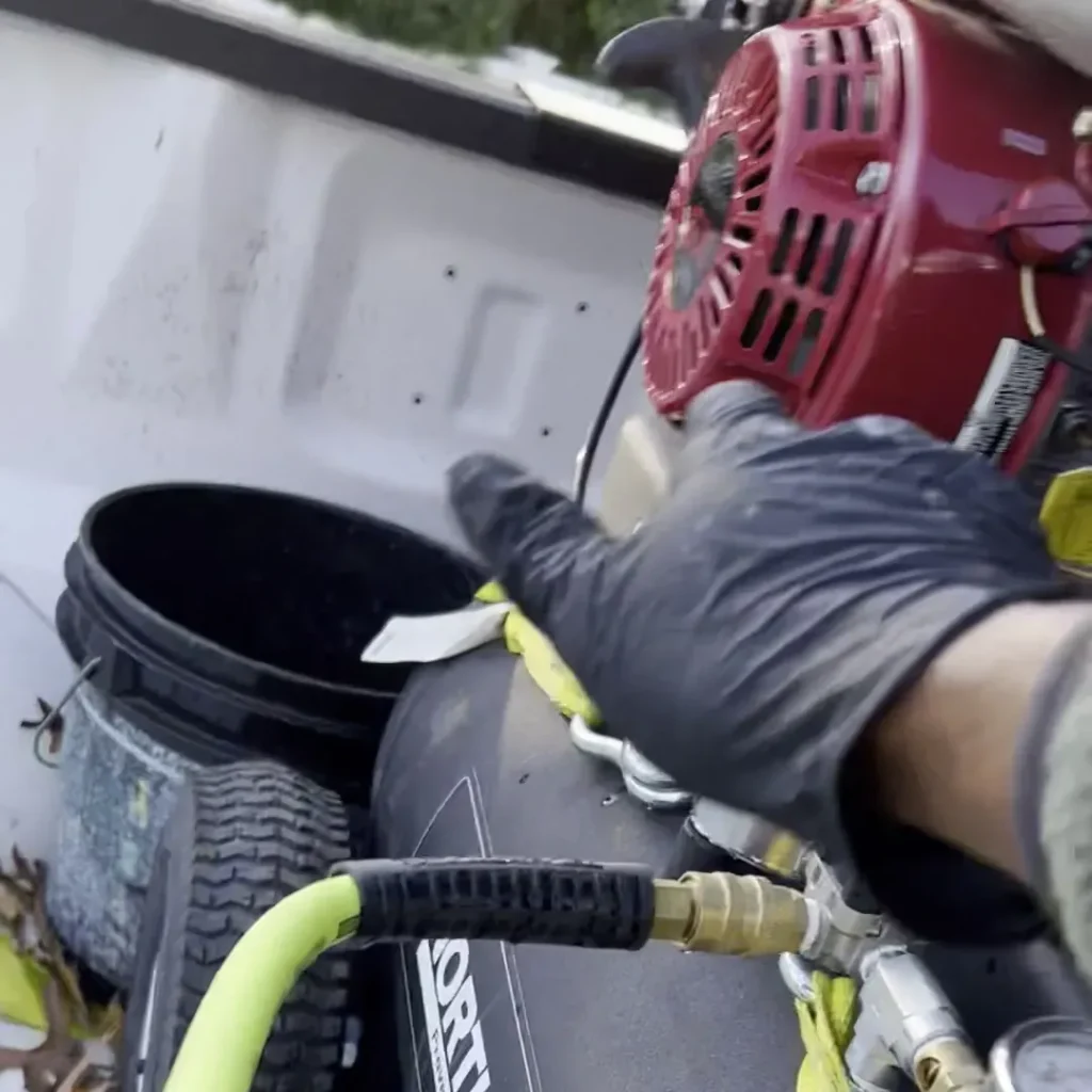 Gloved hand on the air hose coupling of a truck-mounted compressor