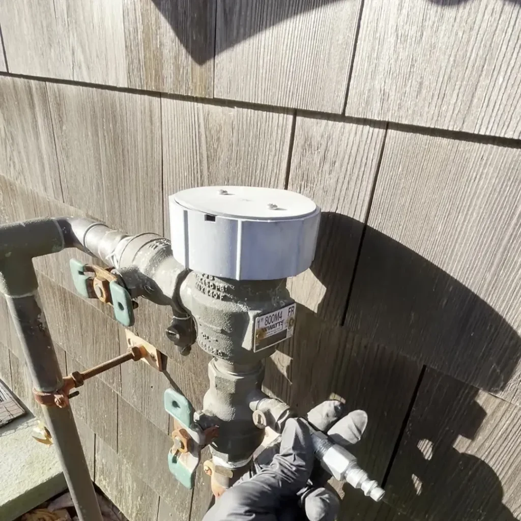 Gloved hand on the ball valves of a backflow preventer