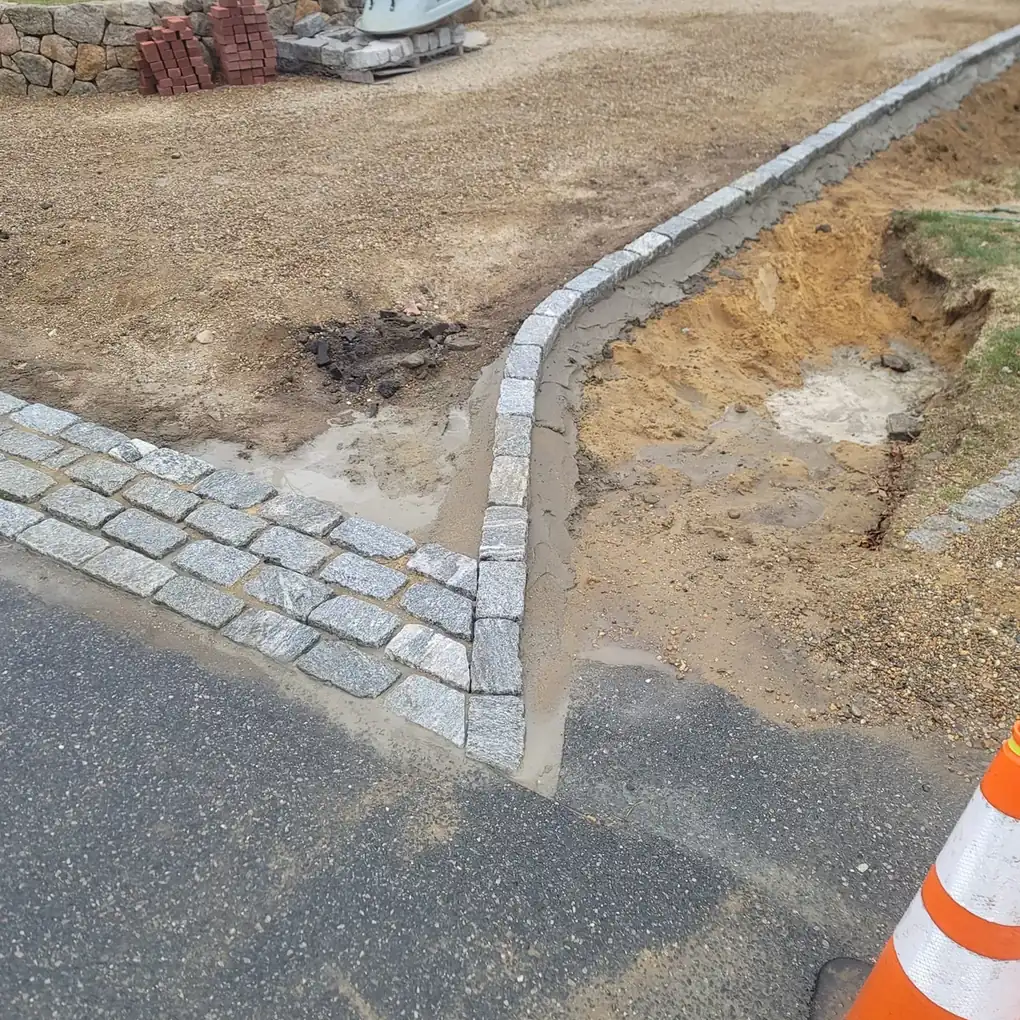 Granite cobblestone courses laid at the road beside a new curb row