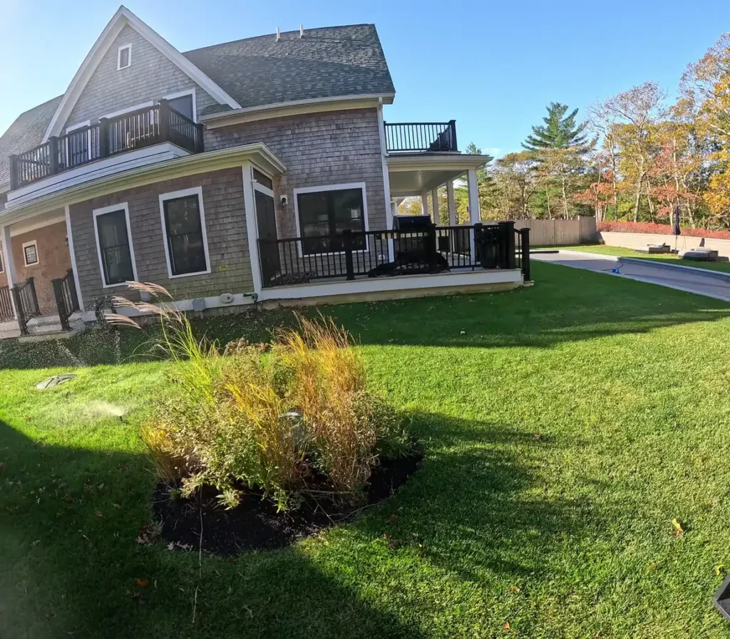 Green lawn with autumn ornamental grasses beside a shingled house
