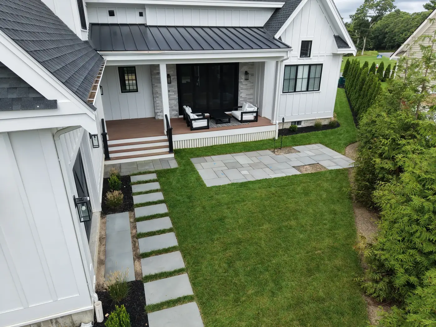 Bluestone stepping stones and patio set into a lawn beside a white house